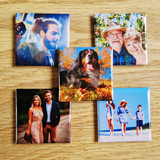 Five magnets arranged on a surface, with four magnets placed in a square pattern and one magnet positioned on top in the middle. The magnets are designed with various images or designs, creating a visually appealing layout with the center magnet slightly raised above the others.