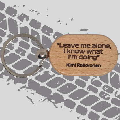 A wooden keychain engraved with the quote "Leave me alone, I know what I'm doing," attributed to Kimi Räikkönen. The text is bold and clear, with a simple, clean design.