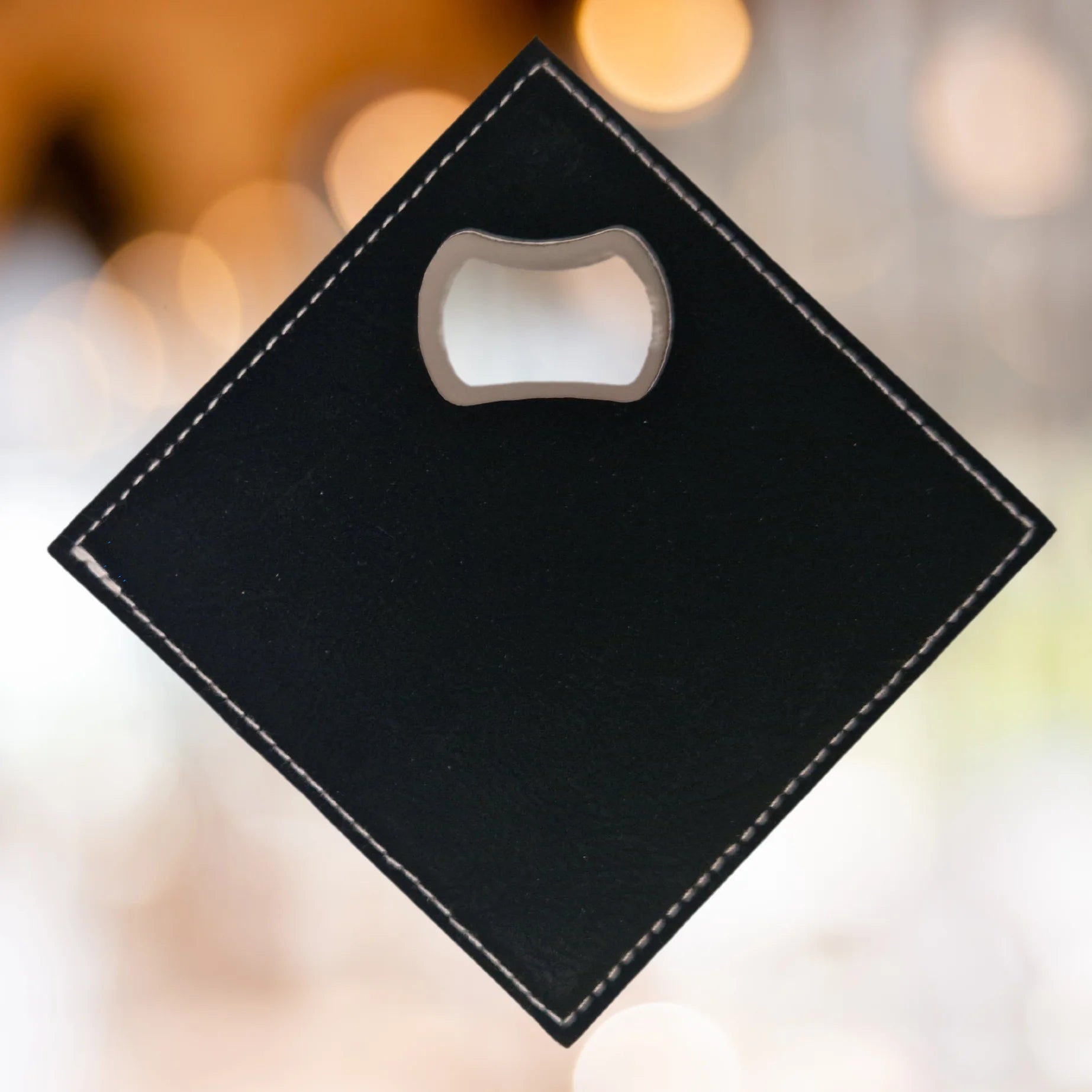 The back of a black faux leather bottle opener coaster, featuring a built-in bottle opener in the corner. The surface is smooth and matte, with no additional markings or designs.