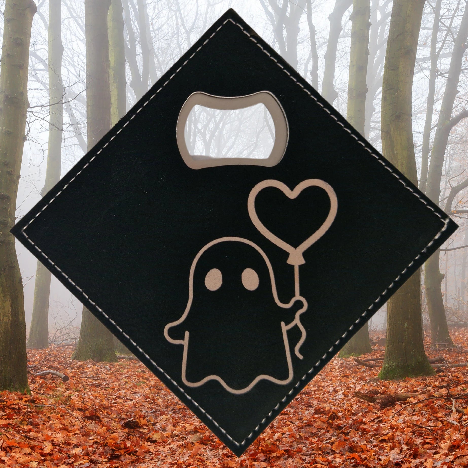 A black faux leather bottle opener coaster engraved with an image of a ghost holding a heart-shaped balloon. The design is whimsical and playful, with smooth, flowing lines depicting the ghost and the floating balloon. The built-in bottle opener is positioned in one corner