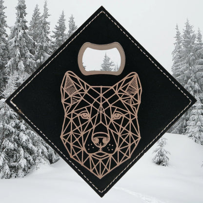 A geometric wolf engraving on a black faux leather bottle opener coaster. The angular, symmetrical design features sharp lines and triangular shapes, creating a bold, modern look. The built-in bottle opener is positioned in one corner.